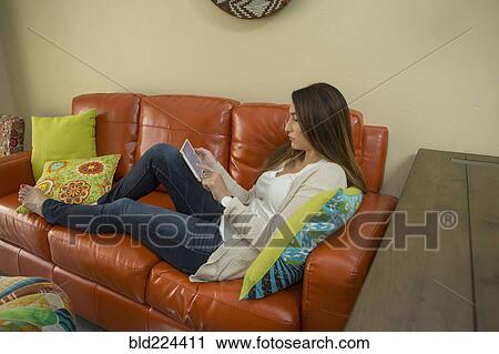 Woman sitting on sofa using digital tablet View Large Photo Image Stock Image - Woman sitting on sofa using digital tablet. Fotosearch