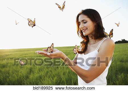 Stock Photography - Woman standing among butterflies in meadow. Fotosearch