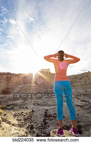 Stock Photography - Woman standing in canyon stretching arms. Fotosearch