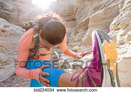 Picture - Woman stretching leg in canyon wearing backpack. Fotosearch