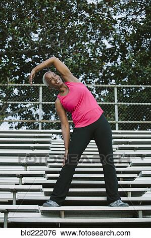 Stock Photograph - Woman stretching on bleachers. Fotosearch