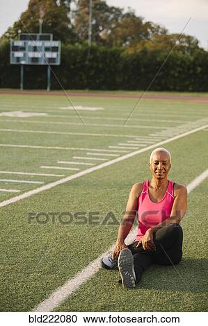 Stock Image - Woman stretching on football field. Fotosearch