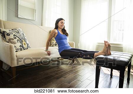 Stock Image - Woman stretching on piano bench. Fotosearch
