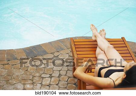 Woman sunbathing next to swimming pool View Large Photo Image Picture - Woman sunbathing next to swimming pool. Fotosearch