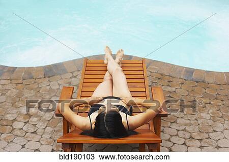 Woman sunbathing next to swimming pool View Large Photo Image Stock Image - Woman sunbathing next to swimming pool. Fotosearch