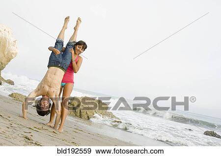 Stock Photo - Woman supporting boyfriend doing handstand. Fotosearch