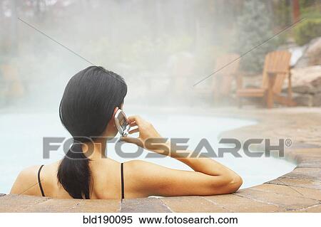 Stock Photography - Woman talking on cell phone in hot tub. Fotosearch
