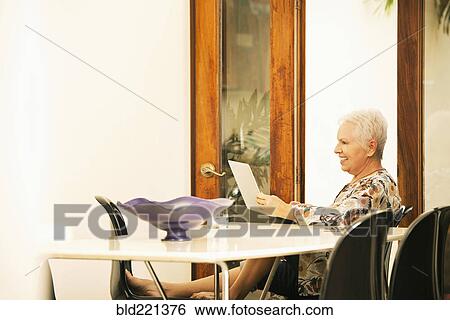 Woman using digital tablet at table View Large Photo Image Stock Photograph - Woman using digital tablet at table. Fotosearch