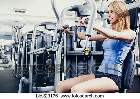 Woman using weight machines in gym View Large Photo Image Stock Photograph - Woman using weight machines in gym. Fotosearch