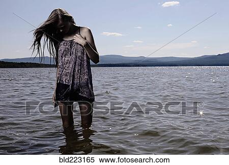 Stock Photography - Woman wading in remote lake. Fotosearch