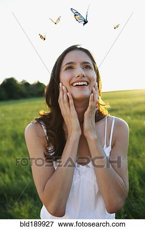 Stock Photo - Woman watching butterflies in meadow. Fotosearch