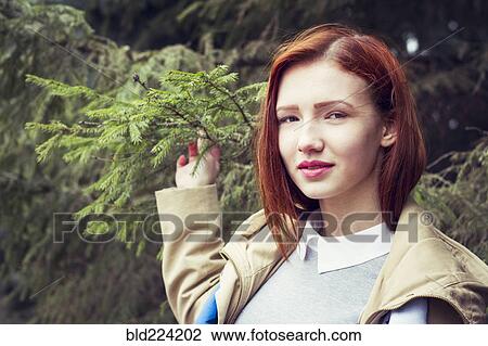 Stock Image - Woman with red hair holding tree branch. Fotosearch