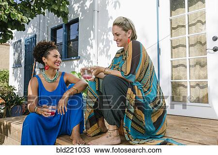 Stock Image - Women drinking juice on front stoop. Fotosearch