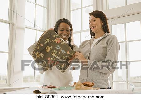 Stock Image - Women holding fabric swatch. Fotosearch