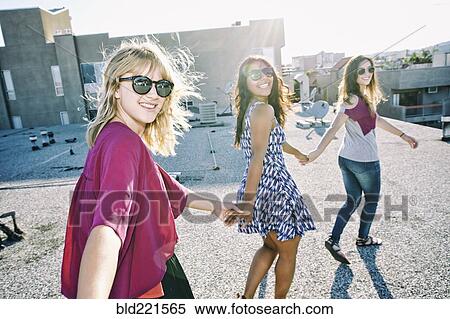 Stock Photography - Women holding hands on urban rooftop. Fotosearch