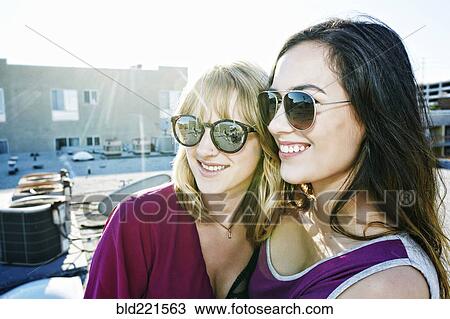 Stock Image - Women hugging on urban rooftop. Fotosearch