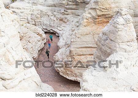 Stock Photo - Women running in canyon wearing backpacks. Fotosearch