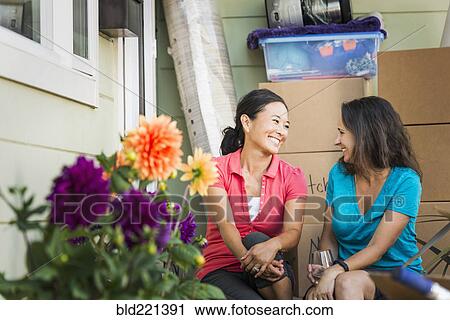 Stock Image - Women smiling outside house. Fotosearch