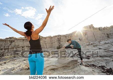 Stock Photograph - Women stretching arms and legs in canyon. Fotosearch