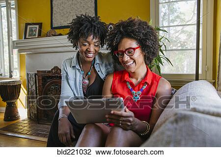 Women using digital tablet on sofa View Large Photo Image Stock Image - Women using digital tablet on sofa. Fotosearch
