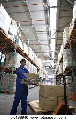 Stock Photograph - Worker stacking boxes in warehouse. Fotosearch