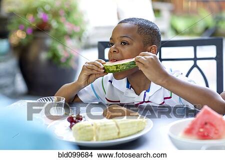 Picture - African American boy eating watermelon. Fotosearch