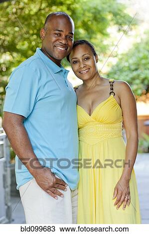 Stock Image - African American couple hugging outdoors. Fotosearch