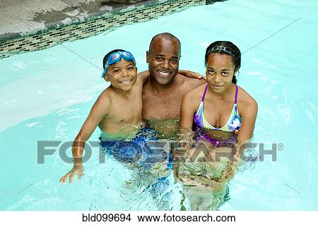 Picture - African American father and children enjoying swimming pool. Fotosearch
