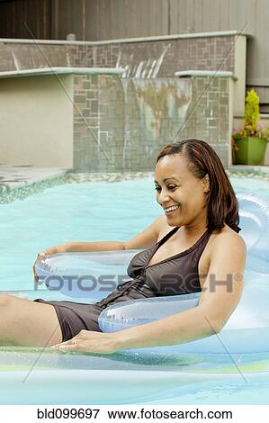 African American woman floating in swimming pool View Large Photo Image Stock Photo - African American woman floating in swimming pool. Fotosearch