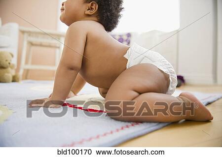 Stock Image - Black baby girl crawling on floor. Fotosearch