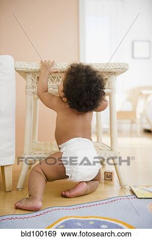 Stock Photo - Black baby girl pulling up on table. Fotosearch
