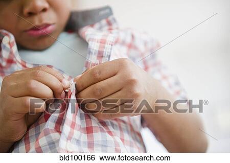 Stock Photograph - Black boy buttoning his shirt. Fotosearch