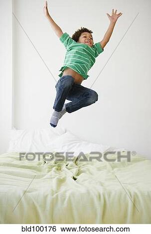 Stock Photograph - Black boy jumping on bed. Fotosearch