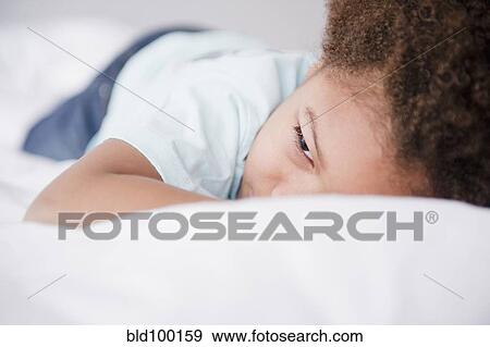 Stock Photo - Black boy laying on bed. Fotosearch