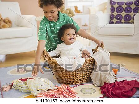 Stock Photo - Black boy putting sister in laundry basket. Fotosearch