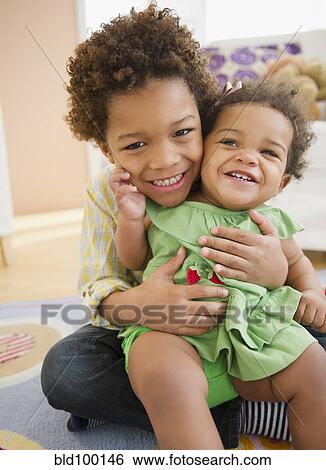Black brother holding sister on his lap View Large Photo Image Stock Photograph - Black brother holding sister on his lap. Fotosearch
