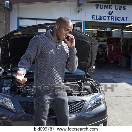 Stock Photo - Black man talking on cell phone in auto repair show. Fotosearch