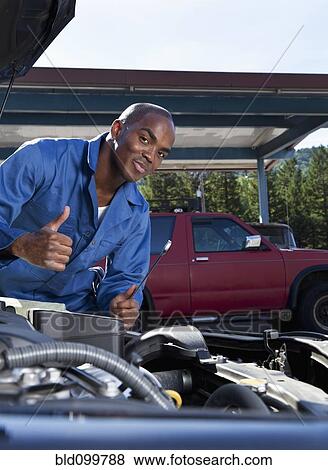 Black mechanic working on car engine View Large Photo Image Stock Photo - Black mechanic working on car engine. Fotosearch