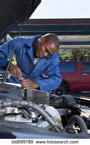 Stock Photo - Black mechanic working on car engine. Fotosearch