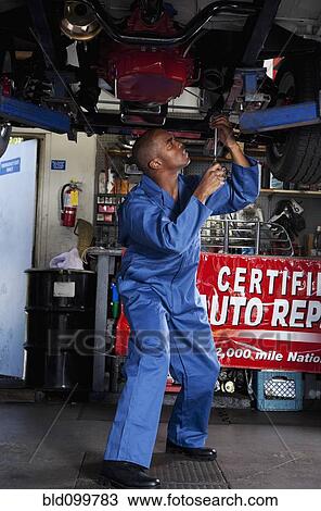 Stock Image - Black mechanic working on car. Fotosearch