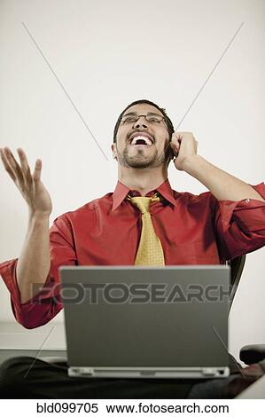 Stock Photography - Businessman with laptop talking on cell phone. Fotosearch