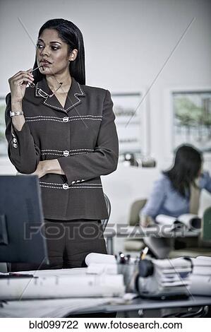 Stock Image - Businesswoman standing in office. Fotosearch