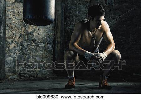 Stock Image - Caucasian boxer drinking water after training. Fotosearch