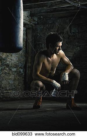Stock Image - Caucasian boxer drinking water after training. Fotosearch