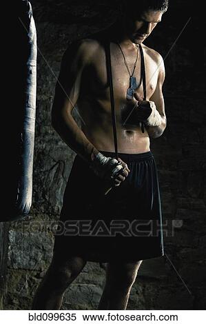 Stock Photography - Caucasian boxer standing near punching bag. Fotosearch