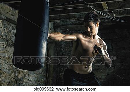 Stock Image - Caucasian boxer training and hitting punching bag. Fotosearch