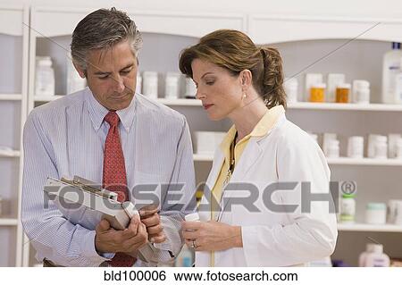 Stock Photograph - Caucasian co-workers working in pharmacy. Fotosearch
