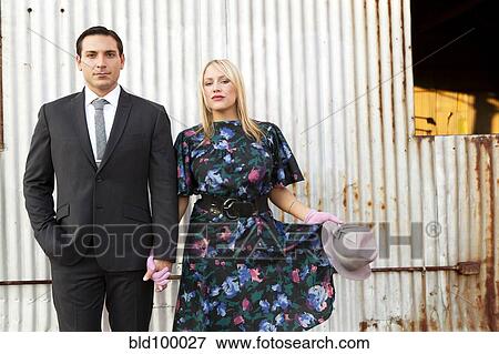 Stock Photo - Caucasian couple in elegant clothes standing near wall. Fotosearch