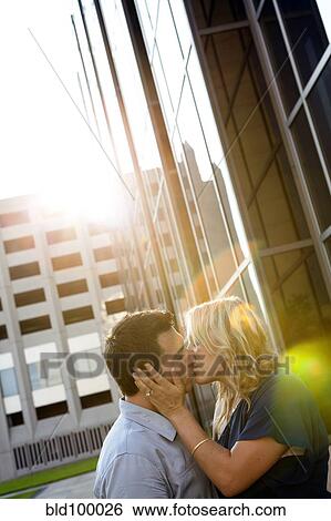 Stock Photograph - Caucasian couple kissing near building. Fotosearch