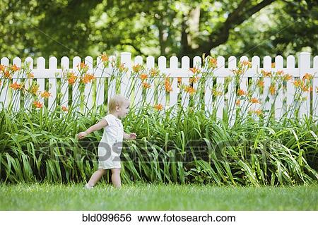 Stock Photograph - Caucasian girl exploring flowers in backyard. Fotosearch